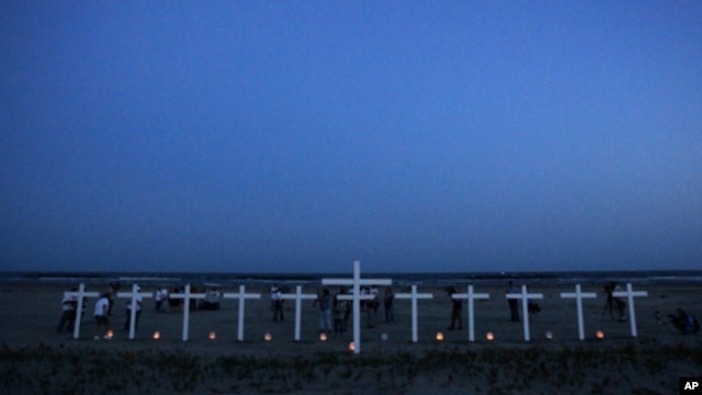 People gather near 11 crosses for the workers who died in the Deepwater Horizon oil rig explosion.