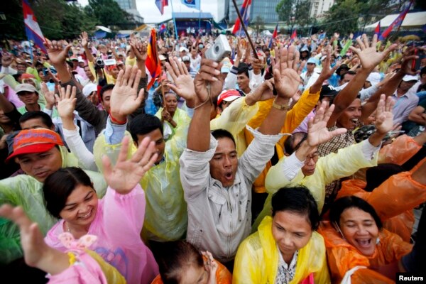 FILE - People raise their arms as they gather during a protest at Freedom Park in central Phnom Penh December 17, 2013.