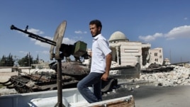 A Free Syrian Army soldier drives by a Syrian tank and a mosque, which were destroyed during fighting with government forces, in Azaz, on the outskirts of Aleppo, Sept. 23, 2012. 