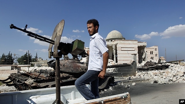 A Free Syrian Army soldier drives by a Syrian tank and a mosque, which were destroyed during fighting with government forces, in Azaz, on the outskirts of Aleppo, Sept. 23, 2012. 