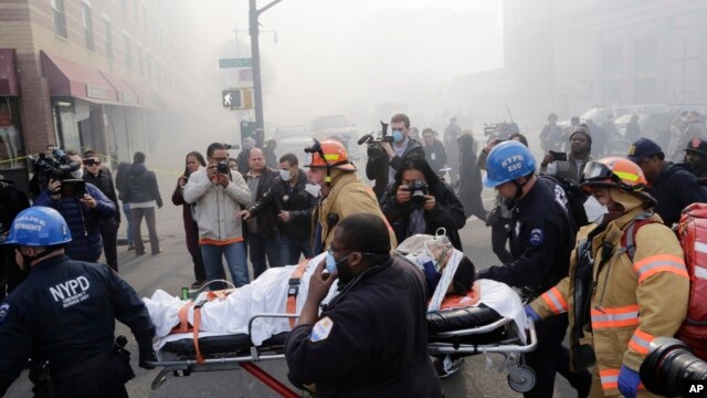 Nhân viên cứu hộ khiêng một người bị thương trên cáng ra khỏi tòa nhà bị sụp đổ ở Harlem, New York, ngày 12/3/2014. 