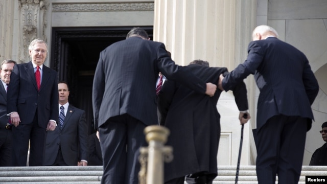 U.S. Senate Minority Leader Mitch McConnell (L) watches as Senator Mark Kirk (2nd R) works his way up the Senate steps with the assistance of Senator Joe Manchin (2nd L) and U.S. Vice President Joseph Biden on his return to the U.S. Senate on Capitol Hill, Washington, January 3, 2013.