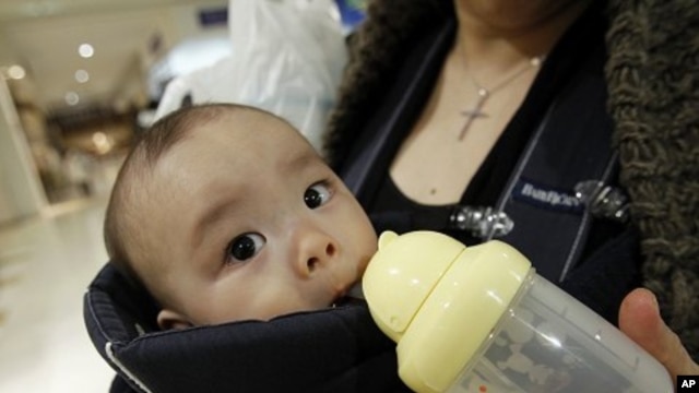 Miyako Ikeda feeds her baby Ryutaro drinking water after buying bottled water at a supermarket in Tokyo, March 25, 2011.
