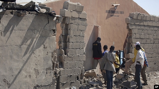 People stand near a damaged wall of a church after an explosion in Jajeri district in Nigeria's northeastern city of Maiduguri, December 23, 2011