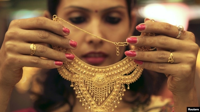 A salesgirl shows a gold necklace to customers at a jewelery showroom in the northern Indian city of Chandigarh, November 11, 2012. 