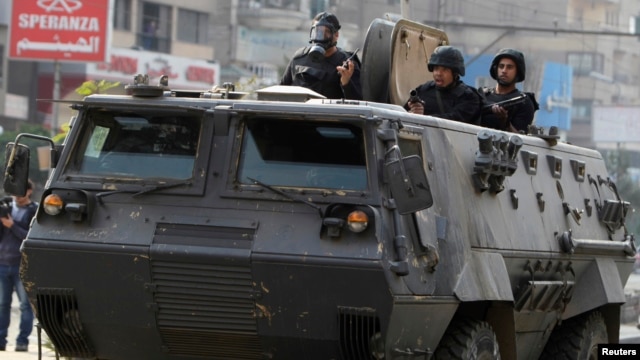 Riot police look from their armoured personnel vehicle during clashes with supporters of Muslim Brotherhood and ousted Egyptian President Mohamed Mursi at Nasr City district in Cairo, Jan. 3, 2014.  
