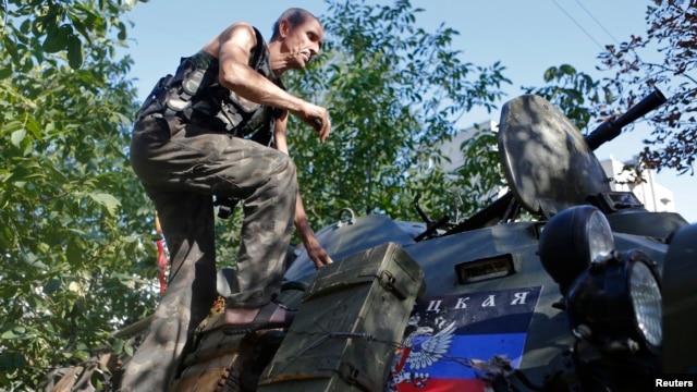 A pro-Russian separatist climbs atop an armored personnel carrier as he guards a position in the eastern Ukrainian town of Ilovaysk Aug. 31, 2014.