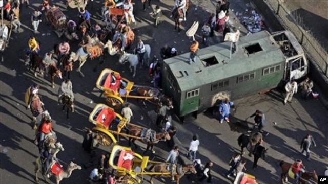 Pro-government demonstrators on horses, camels, and horse-drawn carriages used in the clashes, retreat back past a police truck that was burned in previous clashes a week ago, near Tahrir square in Cairo, Egypt, February 02, 2011.
