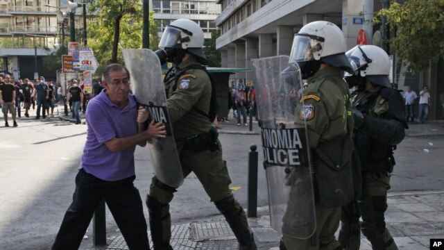 A riot policeman pushes an elderly protester with his shield during clashes during the 24-hour nationwide general strike in Athens, October 18, 2012.
