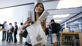 A customer shows her new iPhone 5 at the Apple store in Hong Kong, September 21, 2012.