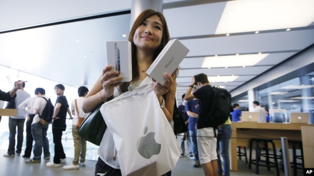 A customer shows her new iPhone 5 at the Apple store in Hong Kong, September 21, 2012.