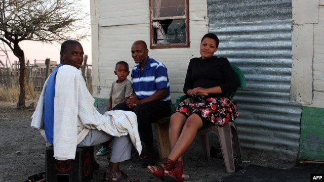 A South African miner and his family sit outside their home in Marikana, September 9, 2012.