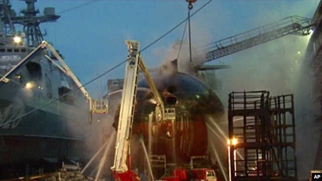 In this video image from Ru-RTR Russian state television channel, firefighters spray water on the Yekaterinburg nuclear submarine in a dock at the Roslyakovo shipyard in the Murmansk region, Russia. A fire that erupted while the Yekaterinburg was in dry-d
