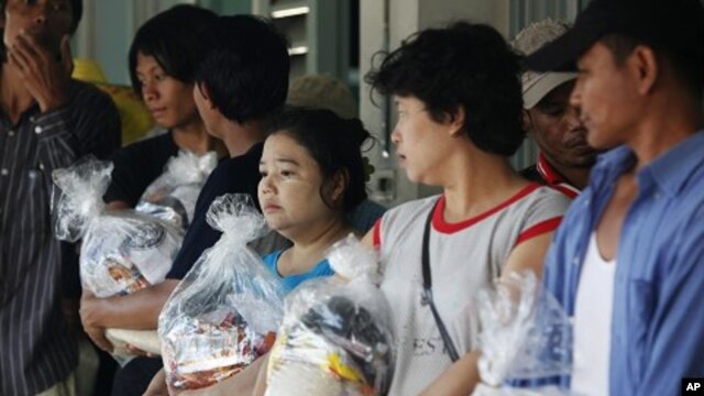 Migrant workers from Burma, who were trapped in floods and have been out of work for weeks, hold food rations in Thailand's Ayutthaya province November 1, 2011. 