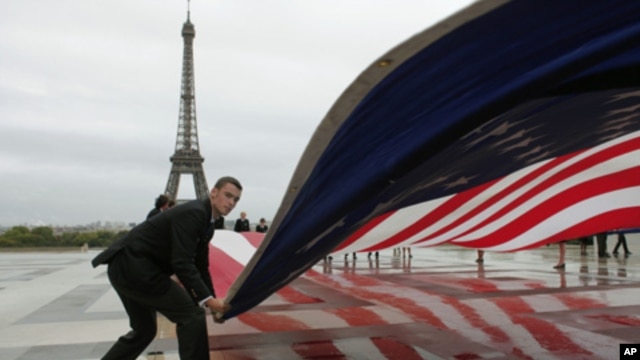 An American flag is unfurled in Paris during a commemoration to mark the 10th anniversary of the Sept. 11 attacks on the United States, at the Trocadero plaza , near the Eiffel tower, Sunday, Sept. 11, 2011.