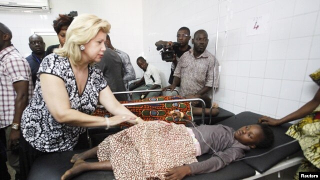 L’épouse du  président Alassane Ouattara, Dominique, au chevet des personnes blessées lors de la bousculade qui s'est produite après des feux d'artifice à Abidjan, 1er Janvier 2013. Plus de 60 personnes ont été écrasées à mort dans une bousculade devant un stade.