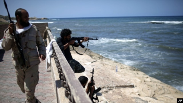 Rebel fighters shoot at what is allegedly Moammar Gadhafi's beach house in Tripoli, August 29, 2011