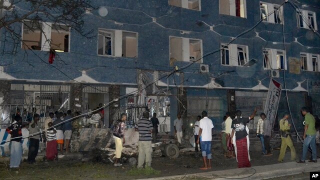Somali security forces and civilians gather outside the Weheliye hotel after it was stormed by militants in Mogadishu, Somalia, July 10, 2015.