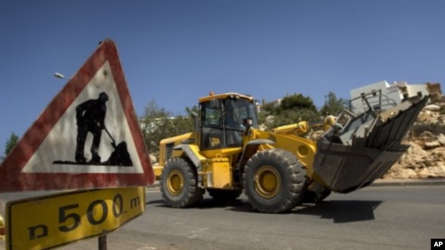 Workers drive ground-moving equipment at a construction site in the Jewish settlement of Revava, near the West Bank city of Nablus (File Photo)