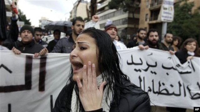A woman shouts slogans as protesters behind her carry a banner condemning Lebanon's current sectarian system of government, Beirut, February 27, 2011