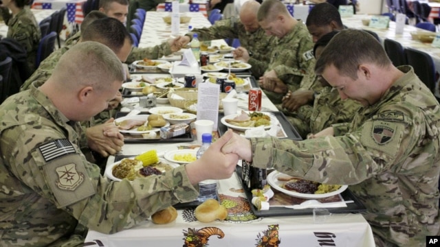 U.S. soldiers pray before eating a Thanksgiving meal at a coalition base dining hall, Kabul, Afghanistan, Nov. 22, 2012. 