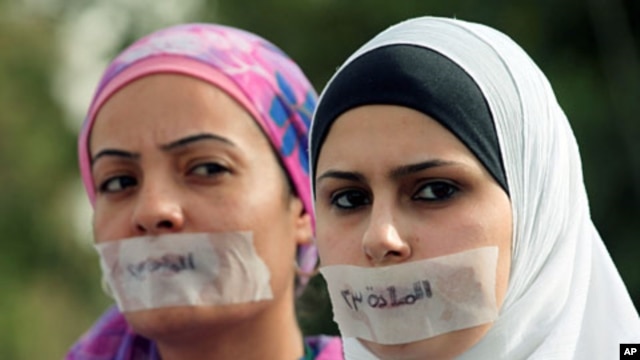 Jordanian journalists protest in front the Jordanian House of Parliament, with their mouths covered with tape and the words "article 23," in Arabic, against proposed changes to the anti-corruption law they believe will muzzle press freedoms, Amman, Septem