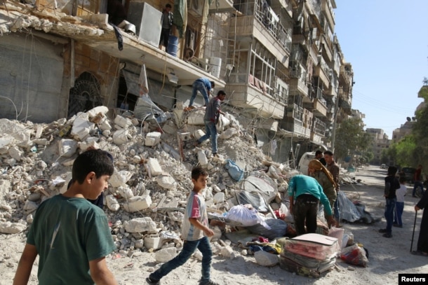 FILE - People remove belongings from a damaged site after an air strike Sunday in the rebel-held besieged al-Qaterji neighbourhood of Aleppo, Syria, Oct. 17, 2016.