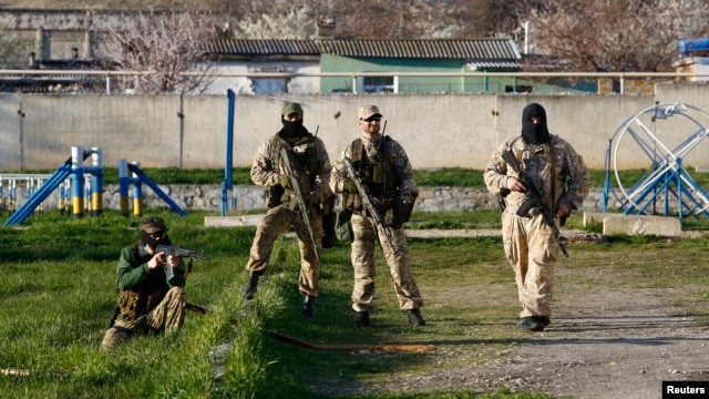 Armed men, believed to be Russian servicemen, stand guard at a military airbase in the Crimean town of Belbek near Sevastopol, Mar. 22, 2014.