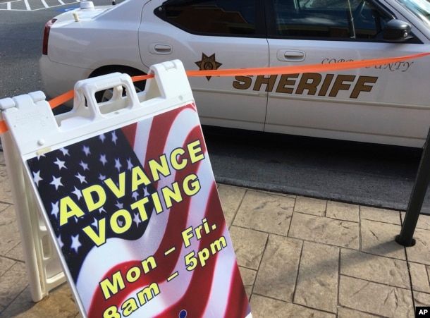 A sign displays absentee voting hours in Marietta, Ga., as a Cobb County sheriff's deputy sits in his vehicle, Oct. 17, 2016. Facing unprecedented warnings of a "rigged" election from Donald Trump, state officials around the country are rushing to reassure the public.r