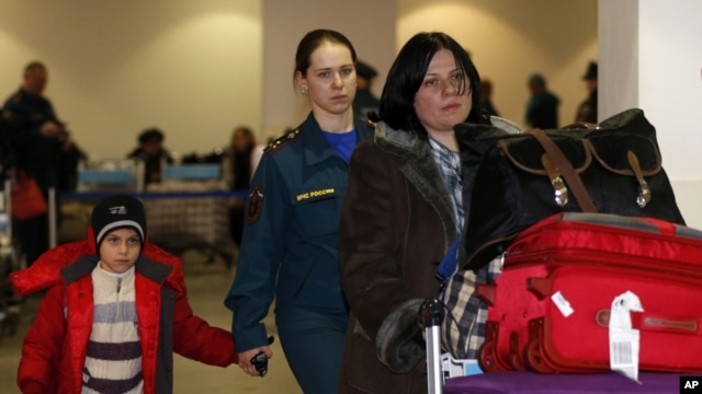A Russian woman and her daughter, left, are escorted by a Russian emergency situation officer leave passport control zone just after arrivingl from Beirut in Moscow Domodedovo airport, January 23, 2013.