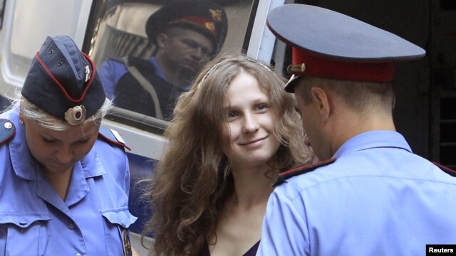 Cô Maria Alyokhina, một thành viên trong ban nhạc Pussy Riot mỉm cười khi cảnh sát áp giải cô ra tòa ở Moscow hôm 31/7/12