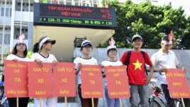 Students hold placards in a protest against a gasoline price hike in front of Petrolimex, in Hanoi, September 16, 2012.
