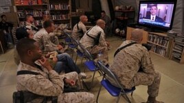 Infantes de Marina de EE.UU., miran un mensaje del presidente Obama en televisión.