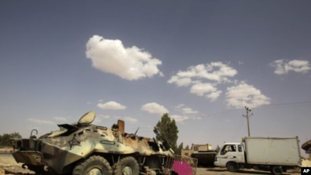 Armoured vehicles belonging to Muammar Gaddafi's troops, which were destroyed by an earlier air strike, are left near the village of Al-Qawalish July 18, 2011