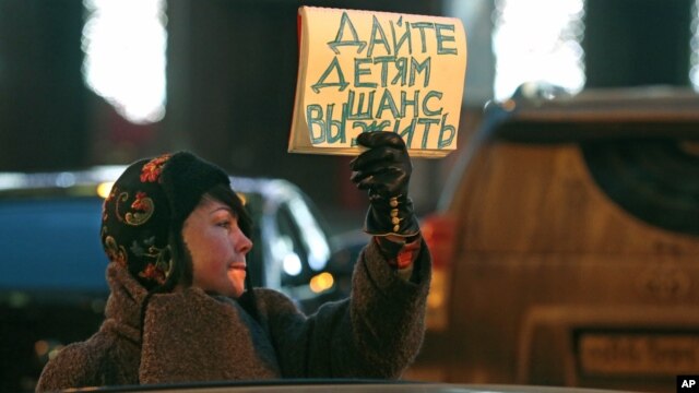 A woman opposing a bill that would ban adoptions of Russian children by Americans holds a sign reading 'Give the children a chance to live' during a picket at the entrance of the State Duma, in Moscow, Russia, December 21, 2012.