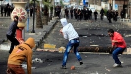 Egyptian protesters throw stones at riot police during clashes near a state security building in Port Said, March 7, 2013.