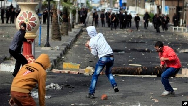 Egyptian protesters throw stones at riot police during clashes near a state security building in Port Said, March 7, 2013.