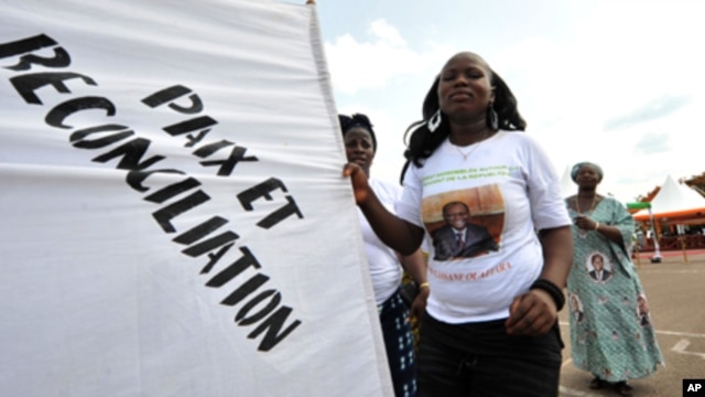 A supporter of Ivorian President Alassane Ouattara dances as she holds a banner reading in French "Peace and reconciliation" during a meeting on April 22, 2012 in Guiglo. 