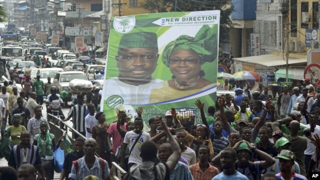 Supporters of the opposition Sierra Leone People's Party (SLPP) march through central Freetown with a placard of presidential candidate Julius Maada Bio and his running mate, Dr. Kadi Sesay, in Freetown, Sierra Leone, October 19, 2012. 