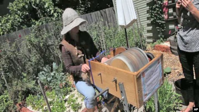 Katherine Jolda pedals to power two large spinning metal drums that brush out wool to be used for locally-made clothing and accessories.