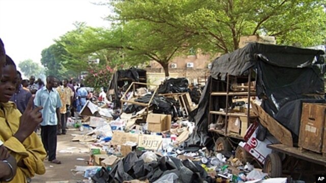 Residents look at debris on the pavement on April 16, 2011 in Ouagadougou after soldiers from three barracks took to the streets of the Burkina Faso capital overnight, firing into the air and pillaging as a mutiny entered its third day