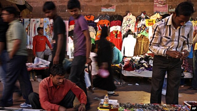 Indians walks past roadside stalls selling clothes and miscellaneous items in New Delhi, India. Indian Finance Minister, Mukherjee, presented India's new budget amid concerns about inflation, the country's falling growth rate, large deficit, FILE March 16