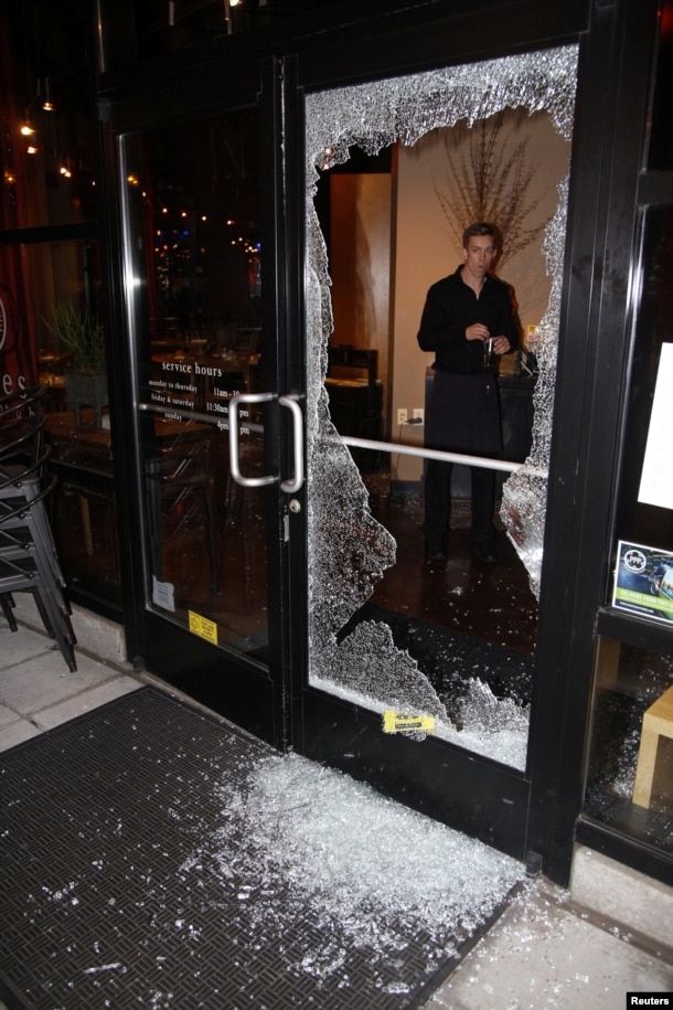 A man looks at broken glass after a riot swept through the area in protest to the election of Republican Donald Trump as President of the United States in Portland, Oregon, Nov. 10, 2016.