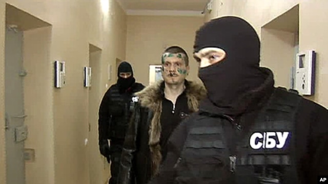 A Russian Channel One undated television grab shows a man identified as Adam Osmayev (C), one of the suspected militants conspiring to kill Vladimir Putin, walking under escort of the masked agents of the Ukrainian Security Service (SBU), shortly after hi