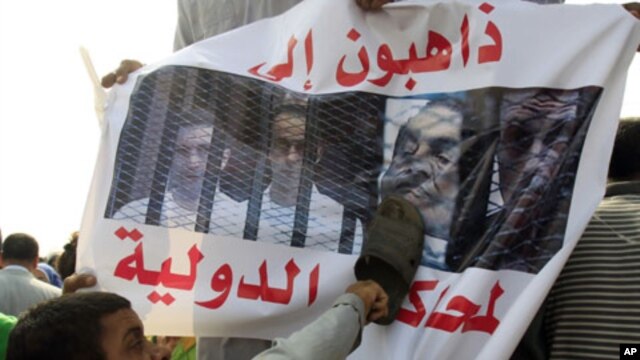 An anti-Mubarak protester uses a shoe to beat an image of former president Hosni Mubarak along with his sons and former Interior Minister Habib al-Adli in front of the police academy where Mubarak is on trial in Cairo, Egypt, September 5, 2011.