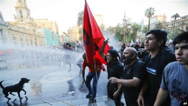 Polisi anti huru hara menyemprotkan air untuk memubarkan para pengunjuk rasa yang berpartisipasi dalam demo KTT Rakyat yang diselenggarakan oleh serikat buruh dan gerakan sosial kiri. Demo ini menentang pelaksanaan KTT 60 negara yang dijadwalkan akan diselenggarakan akhir pekan ini di Santiago, Chile (25/1).