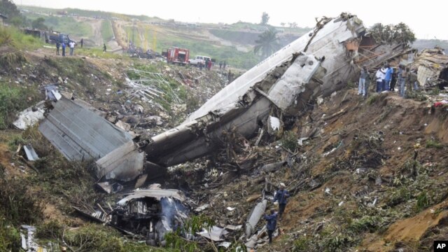 Rescue workers walk among the crash site of a cargo airplane near the airport at Brazzaville in the Republic of Congo on Dec. 1, 2012.