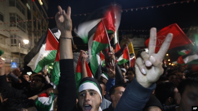 Palestinians celebrate as they watch a screen showing the U.N. General Assembly vote on a resolution to upgrade the status of the Palestinian Authority to a non-member observer state, in the West Bank city of Ramallah, Nov. 29, 2012.