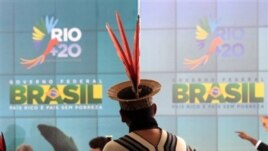 An Ashanink indigenous man stands before a poster promoting the launch of the Rio + 20 sustainable development conference in Brazil