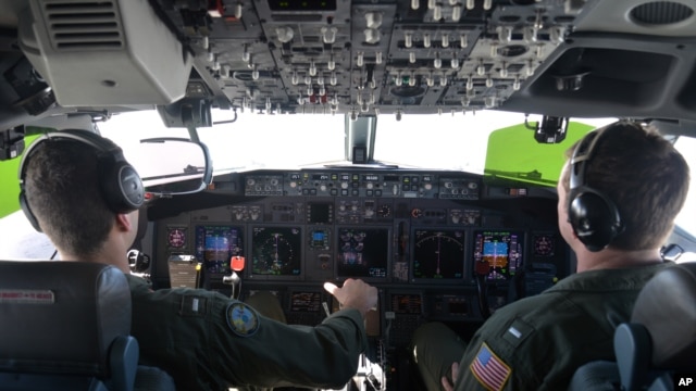 FILE - Lt. j.g. Kyle Atakturk, left, and Lt. j.g. Nicholas Horton, pilot a U.S. Navy P-8A Poseidon during a mission to assist in search and rescue operations for Malaysia Airlines flight MH370, March 19, 2014.
